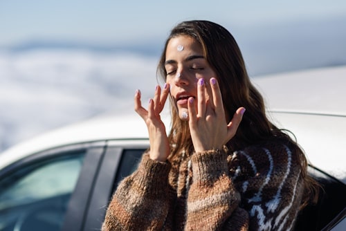 Image of young woman putting sun screen on her face