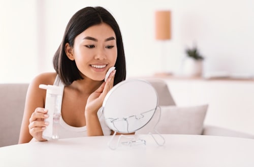 Woman cleaning face with toner