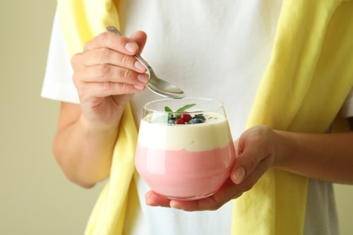 Young woman eats berry yogurt smoothie