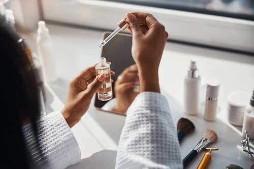 Woman on her vanity table holding face serum