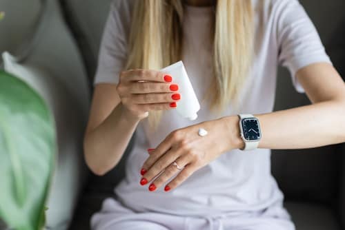 Young woman squeezing cream to back of hands