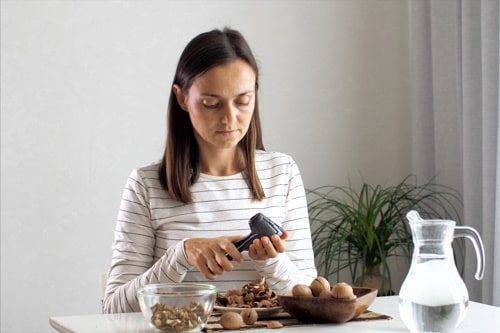 Young woman is cracking a walnuts at at home 