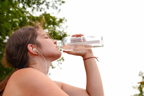 Young woman listens to music drinks water 
