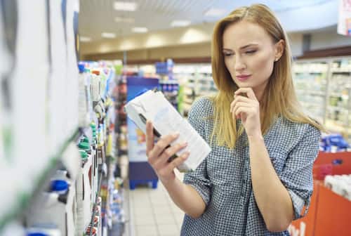 Woman looking at ingredients of milk jug in supermarket