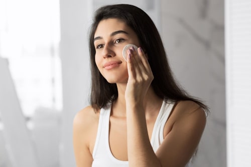 Woman cleaning her face with skin care product