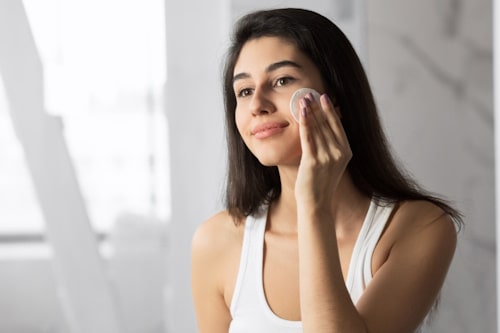 Woman exfoliating her face with cotton pad