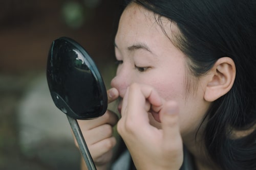 Woman checking acne with motorcycle mirror