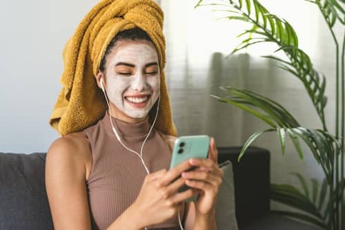 Woman sitting on couch smiling with face mask