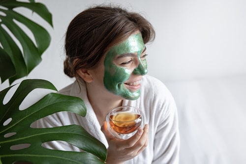 Young woman with green tea mask on face 