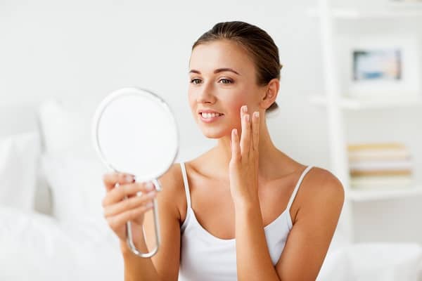 Woman looking in the mirror touching her cheeks