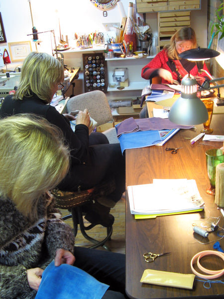 Three women working in the studio with their fiber artworks.