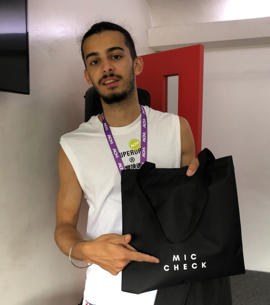 Music student holding black Mic Check Tote bag by Goodstart Jones 