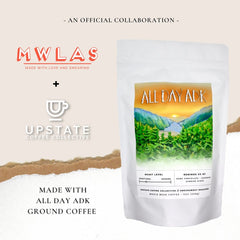 Left side of image shows the MWLAS red and white logo, paired with the white Upstate Coffee Collective logo. Image announces an official collaboration between both brands, highlighting a bag of coffee from the Upstate Coffee Collective, showing that MWLAS is providing a coffee scrub made with this coffee.