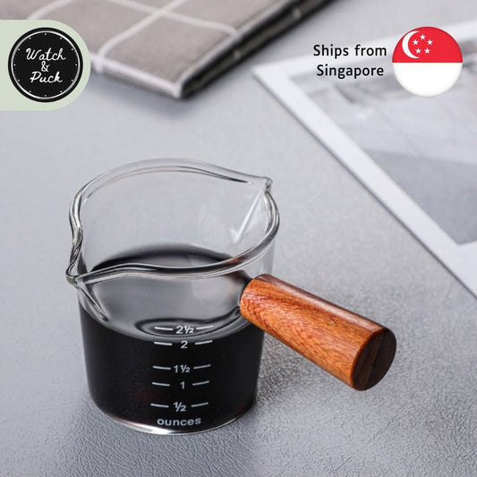 https://cdn.shopify.com/s/files/1/0616/5518/7669/products/espresso-shot-measuring-glass-dual-sprout-dual-shot-25-ounces-70ml-glass-cup-and-wooden-handle-394565_533x.jpg?v=1675178017