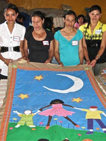 Honduran Women showing a finalized commissioned banner for the Jubilee Center in Dallas