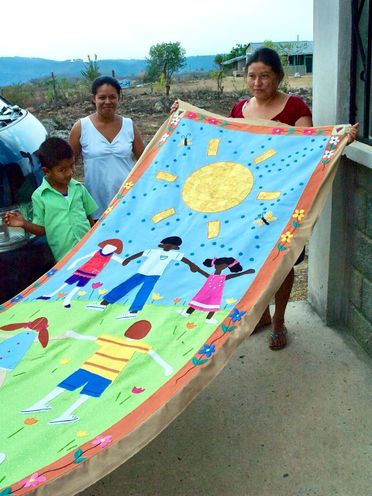 Honduran Women showing a finalized commissioned banner for the Jubilee Center in Dallas