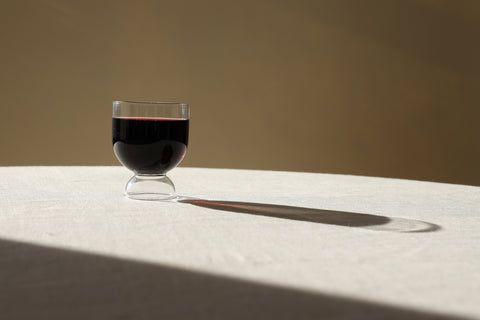 Wine glass on a table casting an artistic shadow