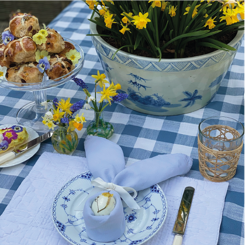 Easter table dressed with flowers, hot cross buns and seasonal flowers