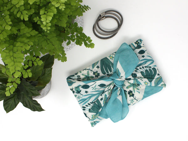 Gift wrapped in a reusable fabric wrapping paper. Cream, blue and green fabric wrap design, with a botanical print.