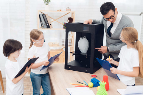 children print different items on 3d printer with a teacher