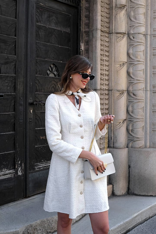 una dama en un vestido de tweed blanco con escote en V