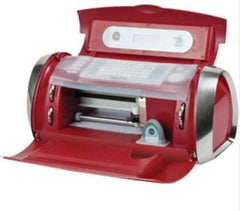 A 2010 Cricut Cake Machine designed specifically for cake decoration. The machine has a sleek and compact design, with a white and silver color scheme. It features a cutting blade and a platform for placing cakes and other edible materials. The Cricut logo is visible on the front of the machine.