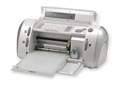 A classic 2005 Cricut Personal machine, showcasing its compact and sleek design. The machine features a cartridge slot, a control panel with buttons and a display screen. The Cricut logo is visible on the front of the machine