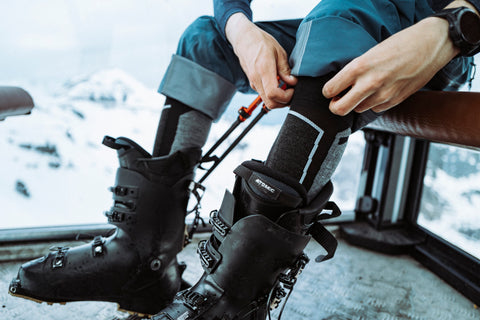 man met ski compressiekousen in skischoen