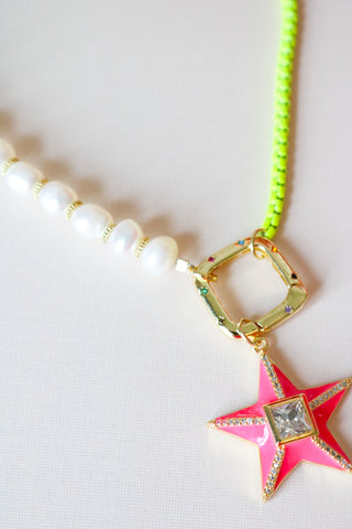 A hot pink neon star pendant hangs from a neon box chain and rice pearl necklace with an embellished box clasp.