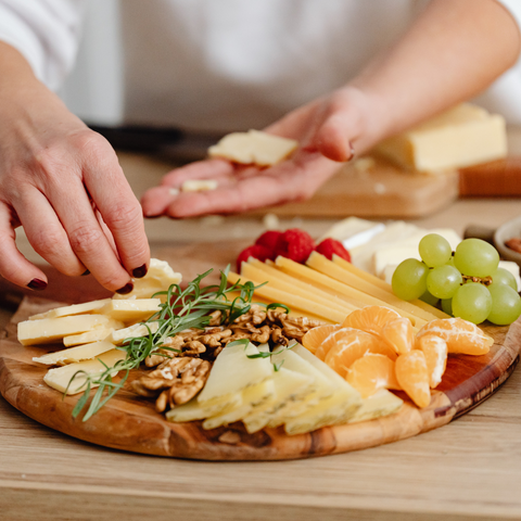 woman placing food on a charcuterie board