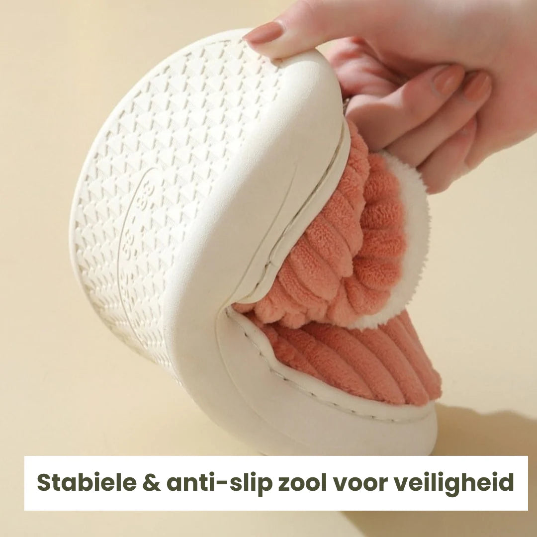 Hand houdt pantoffel vast en laat de witte anti-slipzool zien.