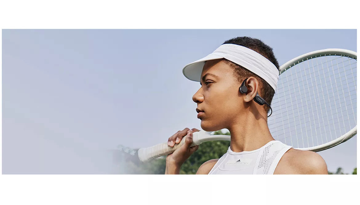 A person is playing badminton while wearing bone conduction headphones.