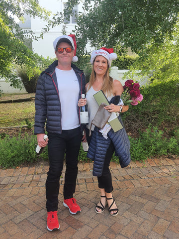 Stan and Michanne in Christmas attire holding Harry Hartman wine