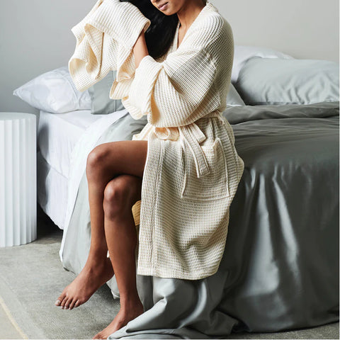 woman sitting on the edge of a bed with a bamboo waffle robe on