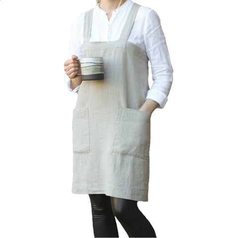 Image of person wearing a linen apron with a mug in one hand and the other hand in the pocket of the apron