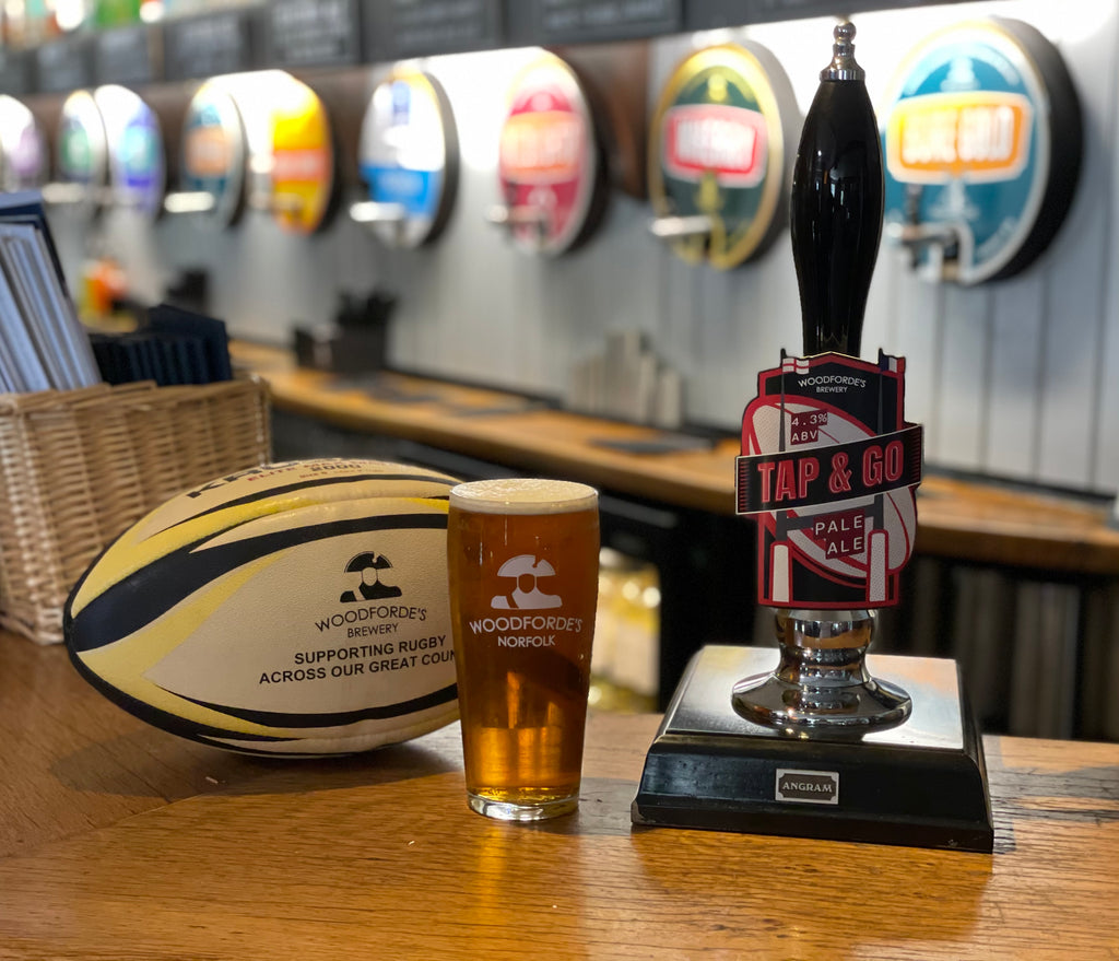 Woodforde's branded rugby ball next to a pint of Tap & Go pale ale