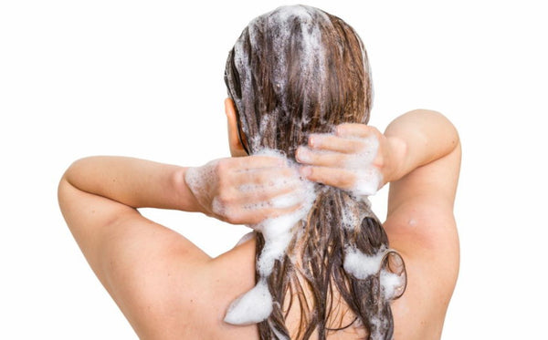 Mujer duchándose con extensiones de cabello con cinta adhesiva