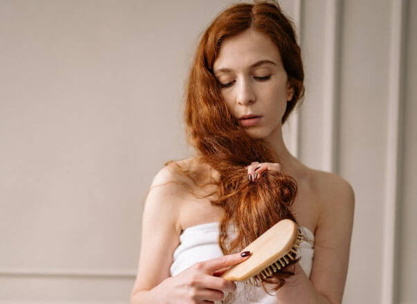 mujer cepillando extensiones de cabello