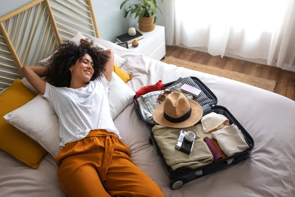 Woman on the bed with an open suitcase beside her