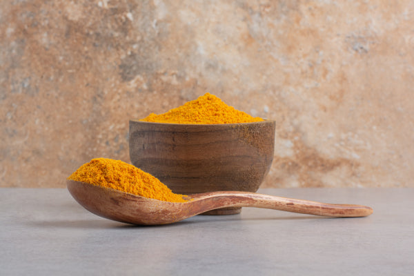 A bowl of turmeric powder with a spoon, representing one of the herbal remedies for pain relief discussed in the MDBiowellness- Plant Medicine post '6 Herbal Remedies for Pain Relief: Natural Pain Relievers That Work,' developed by Doctors.