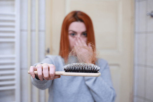 A person gently applying topical treatment to their scalp