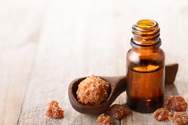 A person holding a bottle of myrrh essential oil with a few drops of oil in it - Uncover the extraordinary Myrrh Oil Benefits for 2023 and Beyond in this insightful post by MDBiowellness- Plant Medicine. Developed by Doctors.