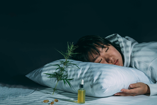 A person peacefully sleeping with a bottle of CBD oil next to them. This image is featured on 'Unlocking the Difference: A Comprehensive Guide to CBD vs CBN for Sleep,' a resource developed by doctors