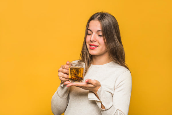 A woman holding a cup of ginger tea, symbolizing one of the herbal remedies for pain relief discussed in the MDBiowellness- Plant Medicine post '6 Herbal Remedies for Pain Relief: Natural Pain Relievers That Work,' developed by Doctors.
