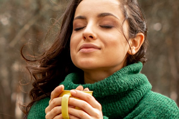 Image for the '6 Herbal Remedies for Pain Relief: Natural Pain Relievers That Work' post by MDBiowellness- Plant Medicine. A woman holding a cup of herbal tea, looking relaxed and content. Developed by Doctors.