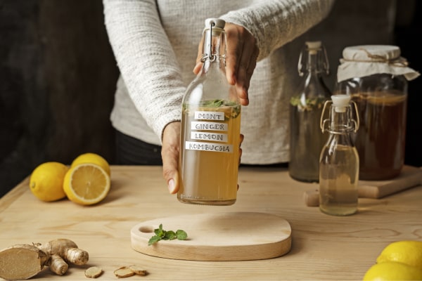 A woman with her hands on her stomach holding a bottle of ginger oil - Uncover the healing Ginger Oil Benefits for Skin, Hair, and Aromatherapy in this comprehensive post by MDBiowellness- Plant Medicine. Developed by Doctors.