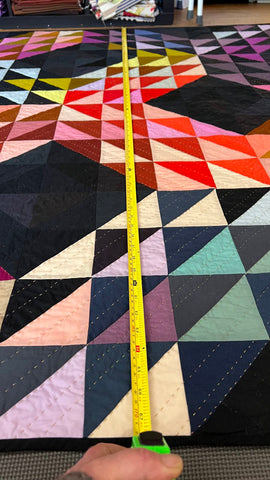 A quilt made of half square triangles, laid out on the floor to block.