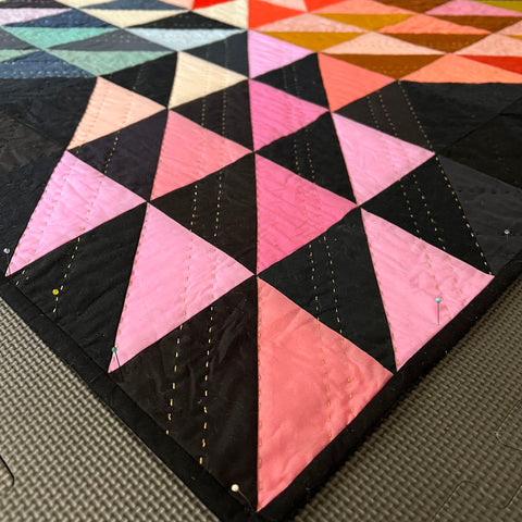 Close up of a half square triangles quilt in multiple colors.