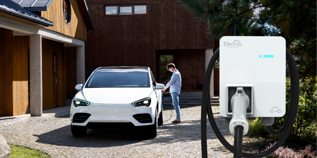 Watti Home Gen 2 electric vehicle (EV) charger in the forefront of an image of man plugging in his EV in front of a modern wooden house and gardens