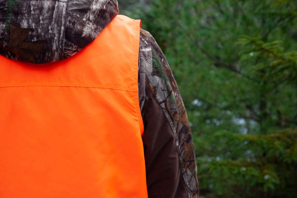 Hunter wears blaze orange vest over camo coat